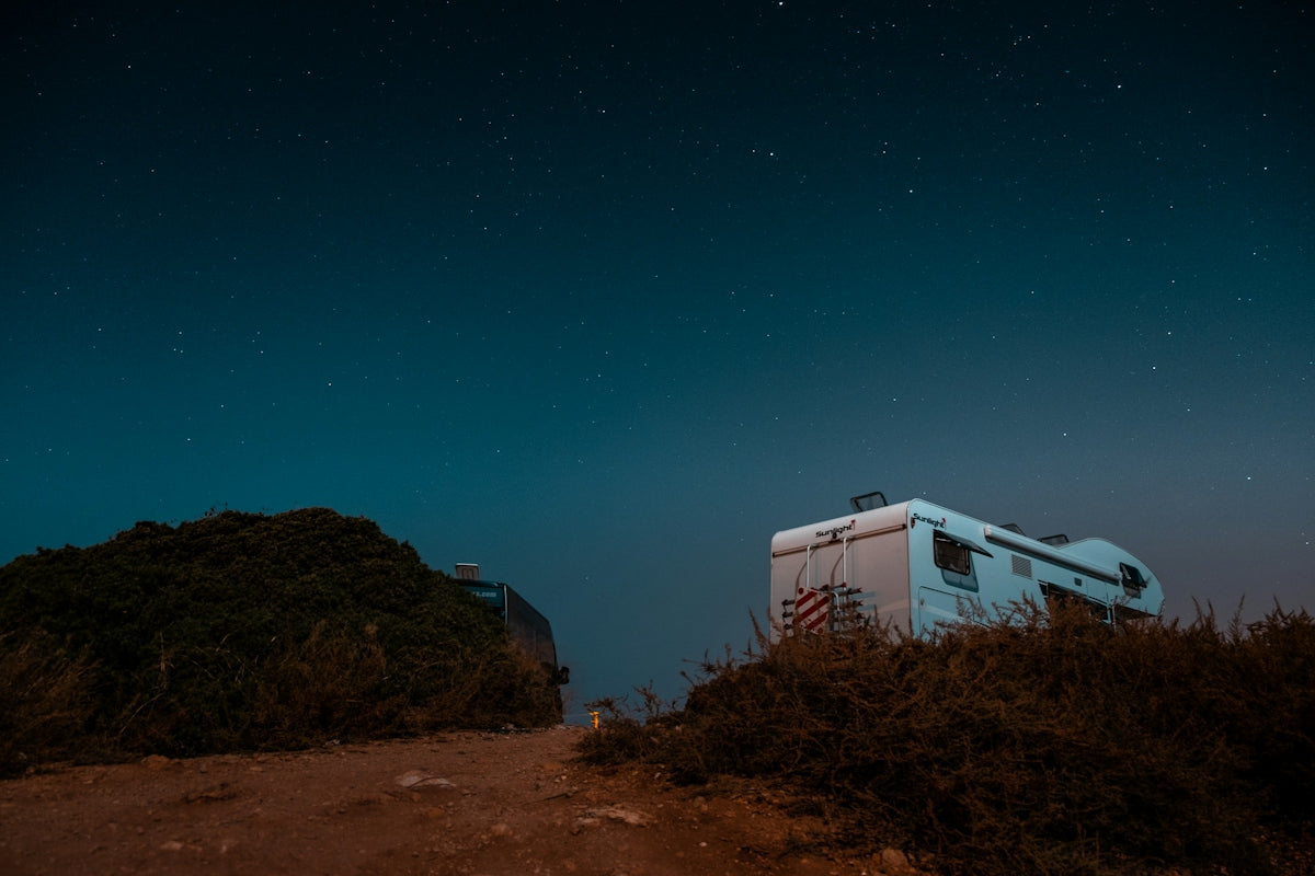 an rv parked on a dirt road at night