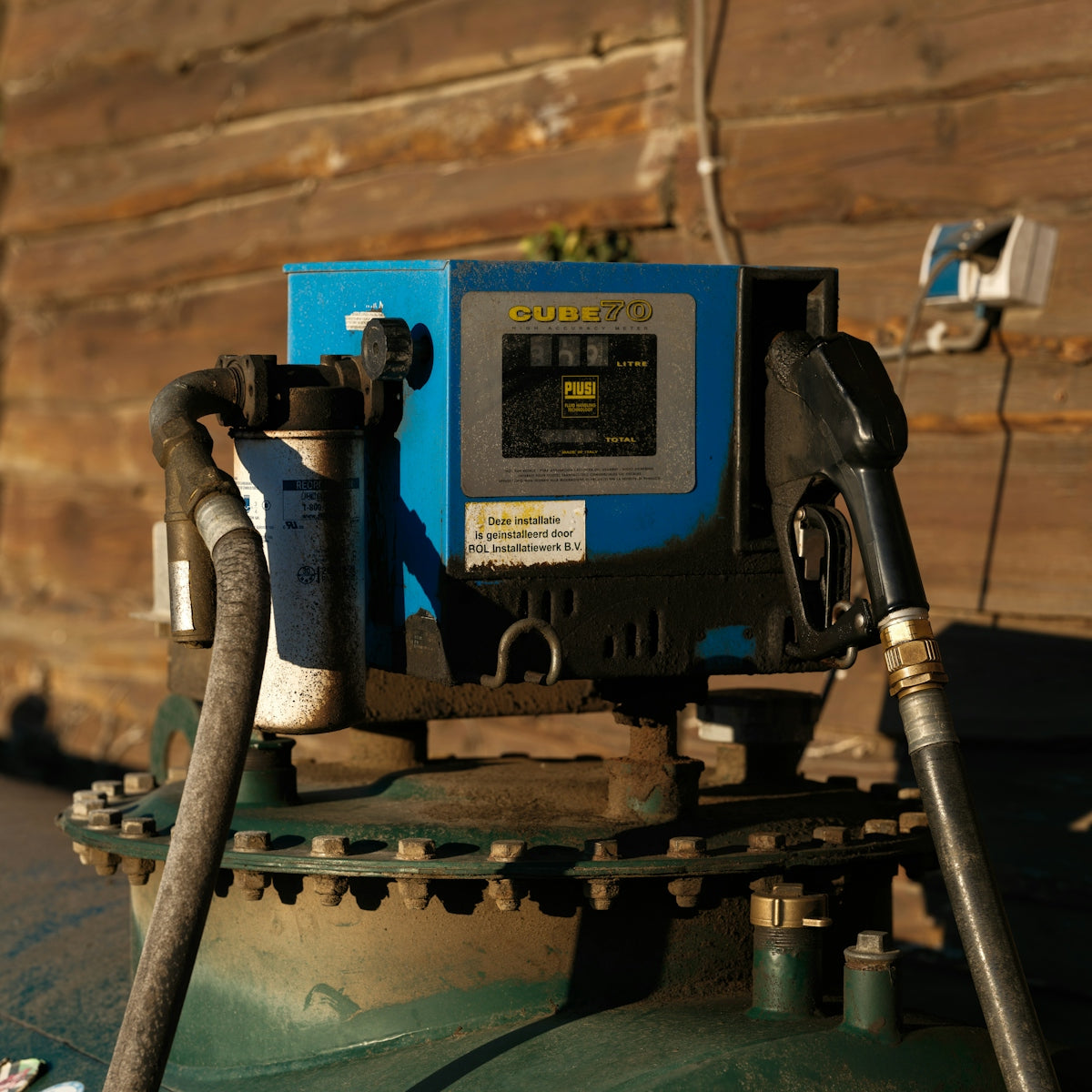 A gas pump sitting next to a wooden wall