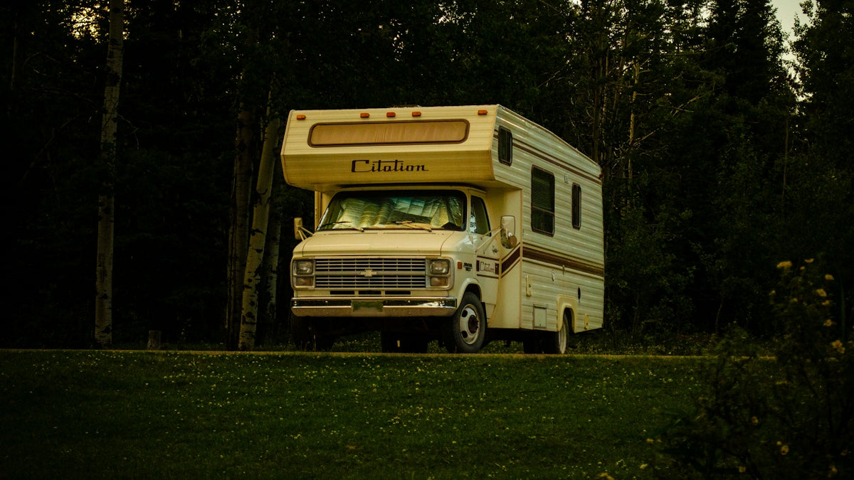 White rv parked on grassy area with trees