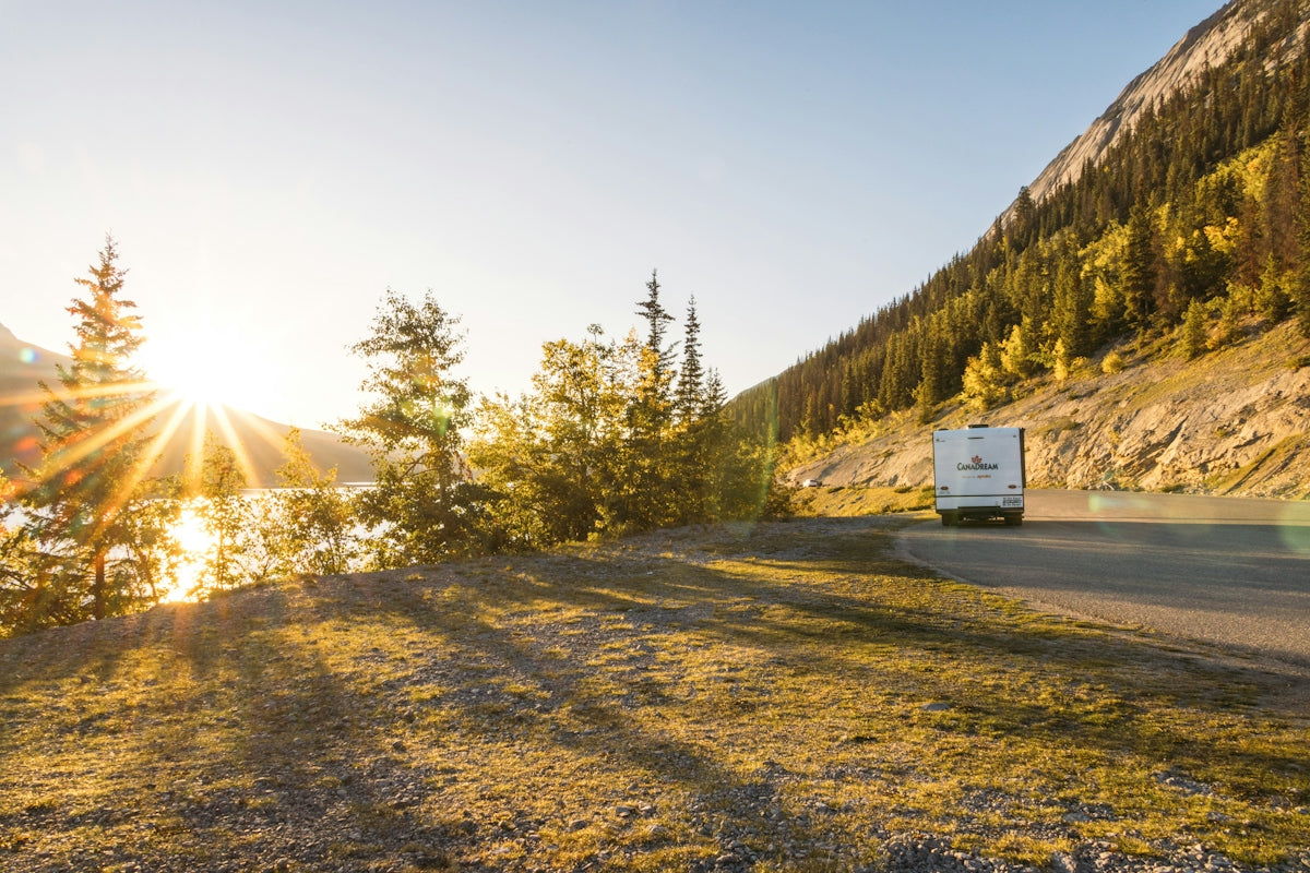 An rv drives along a scenic mountain road at sunset