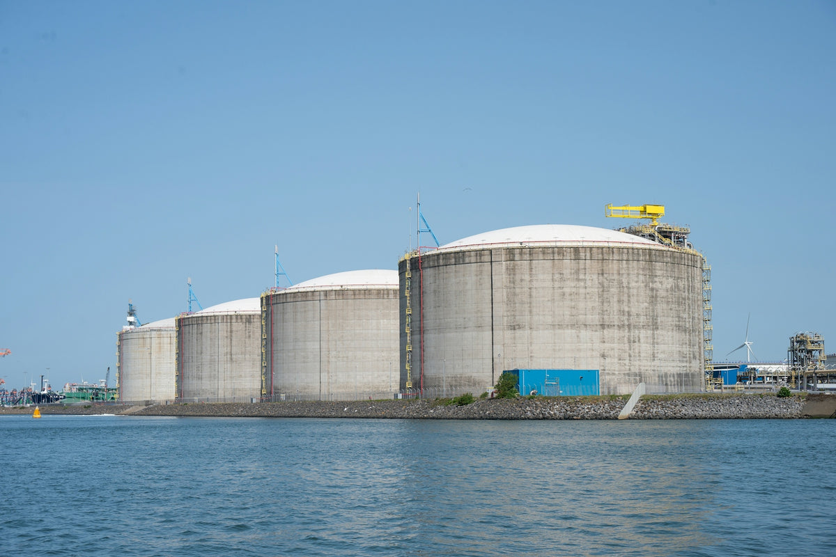 Industrial storage tanks by the water under a clear sky