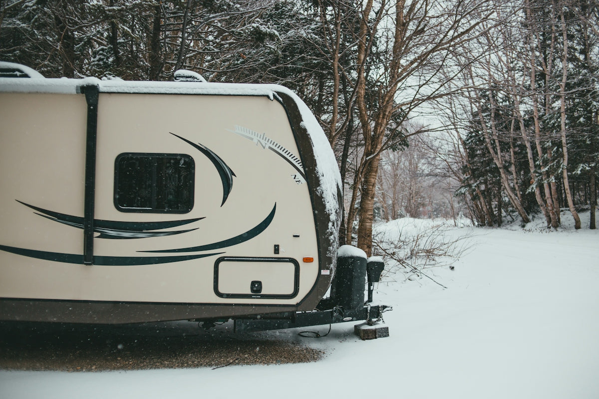 white and black rv trailer on snow covered ground