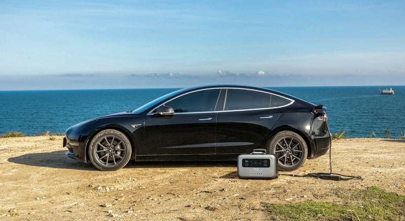 a black car parked on a dirt road next to the ocean